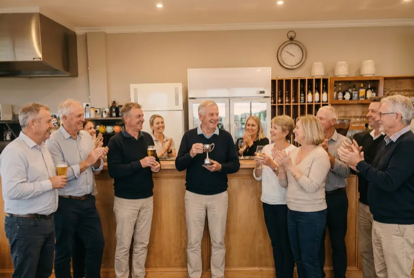 A club presentation night at the timber bar in the clubhouse, a trophy held up and the room applauding
